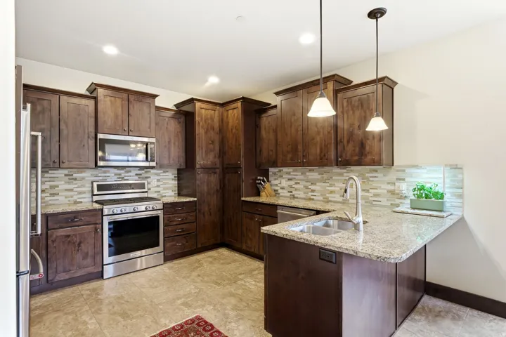 Well-appointed kitchen featuring dark wood cabinetry, granite countertops, and a tiled backsplash