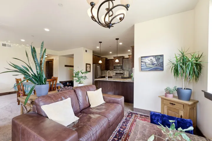 Open-concept living area featuring a kitchen with dark wood-finish cabinetry, a tile backsplash, and stainless steel appliances