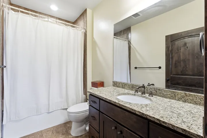 Bathroom featuring a wood-finish vanity with a granite countertop and an undermount sink