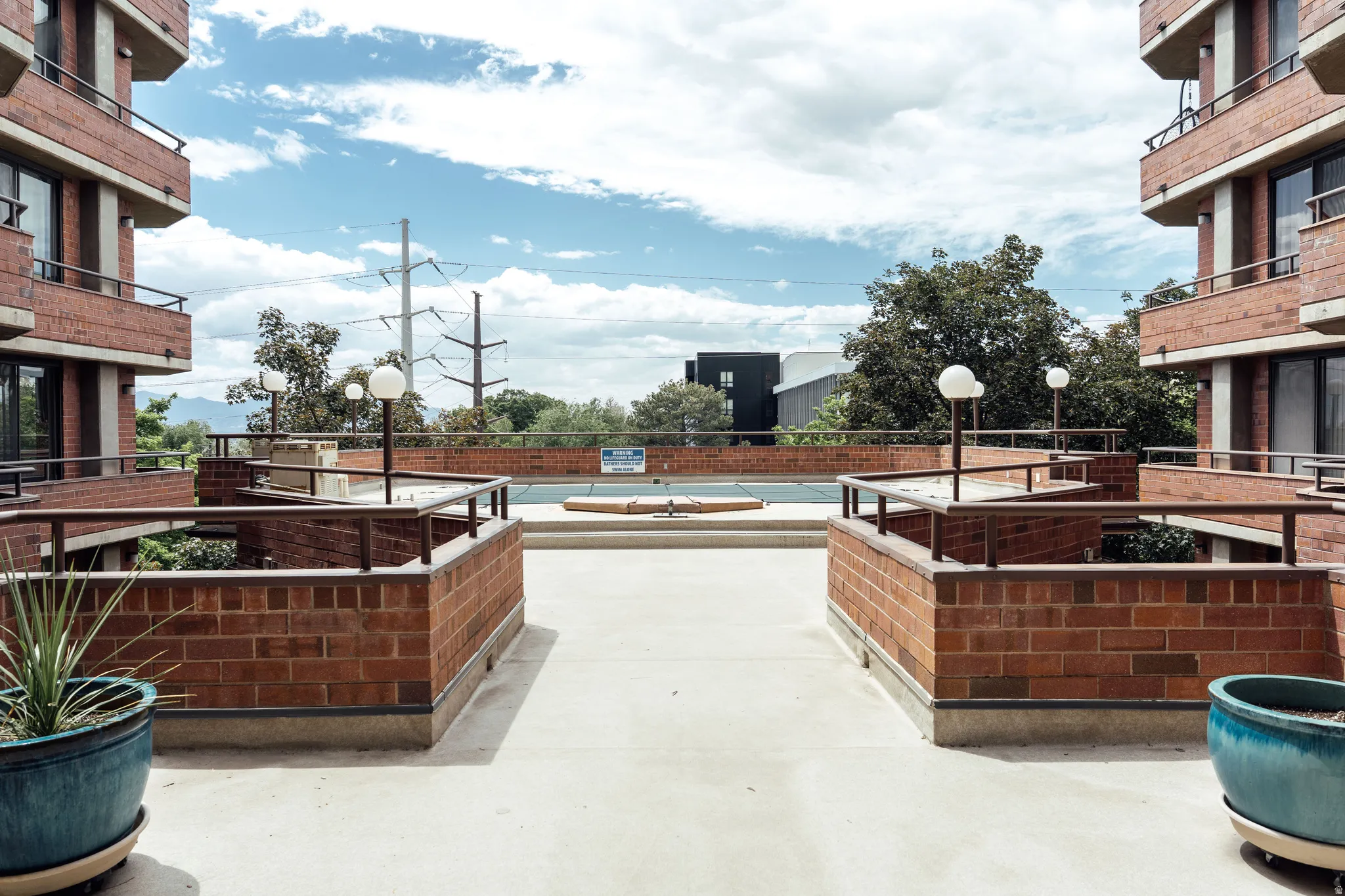 Exterior deck area featuring brick half-walls, metal railings, and integrated sphere light fixtures