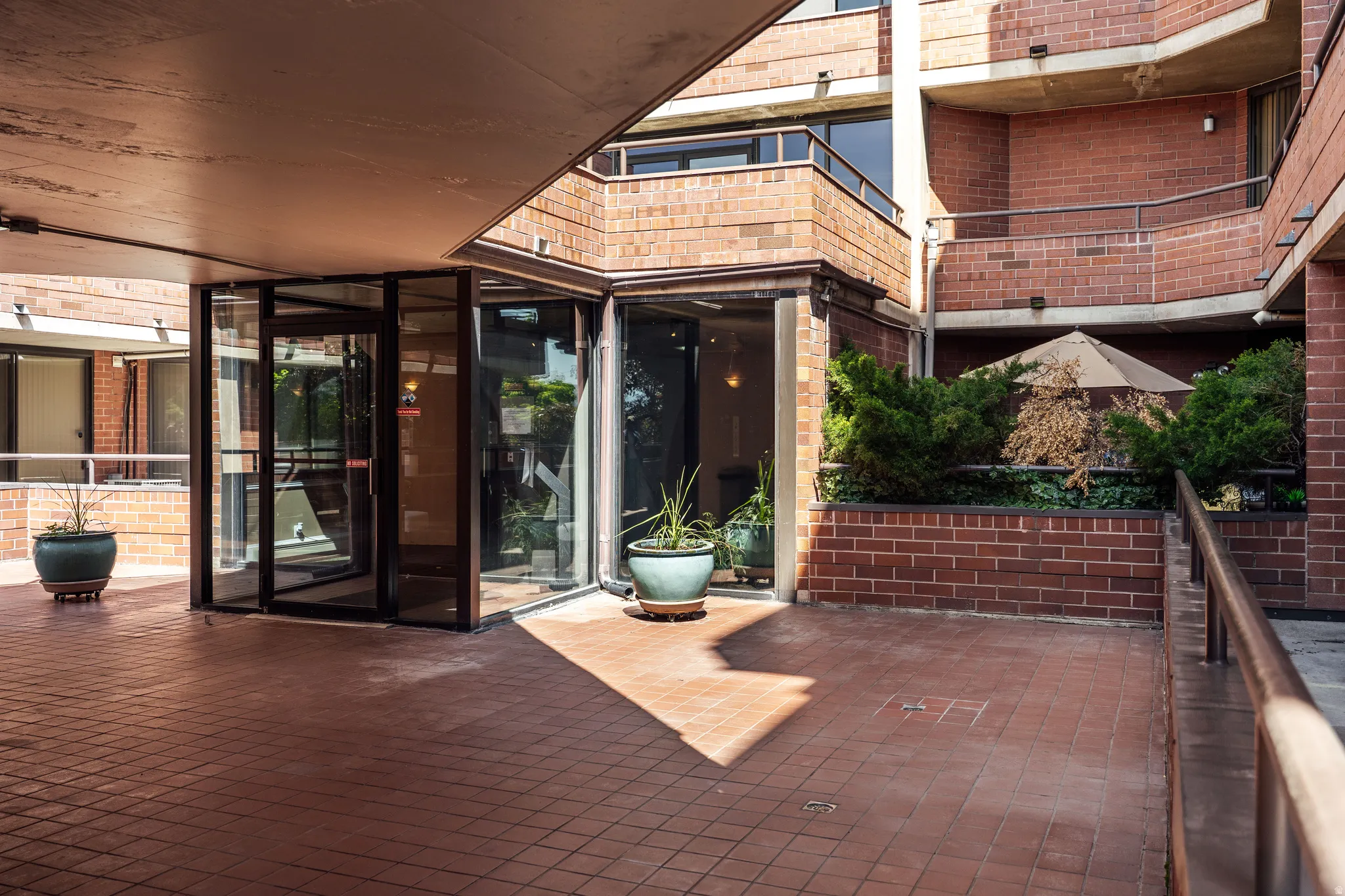 Brick facade entrance with a covered, tiled walkway, glass double doors, and integrated planters