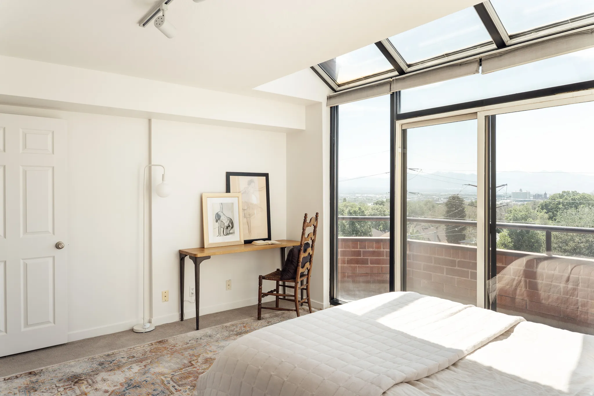 Sliding glass doors opening to a balcony with brick railing, offering expansive distant scenery