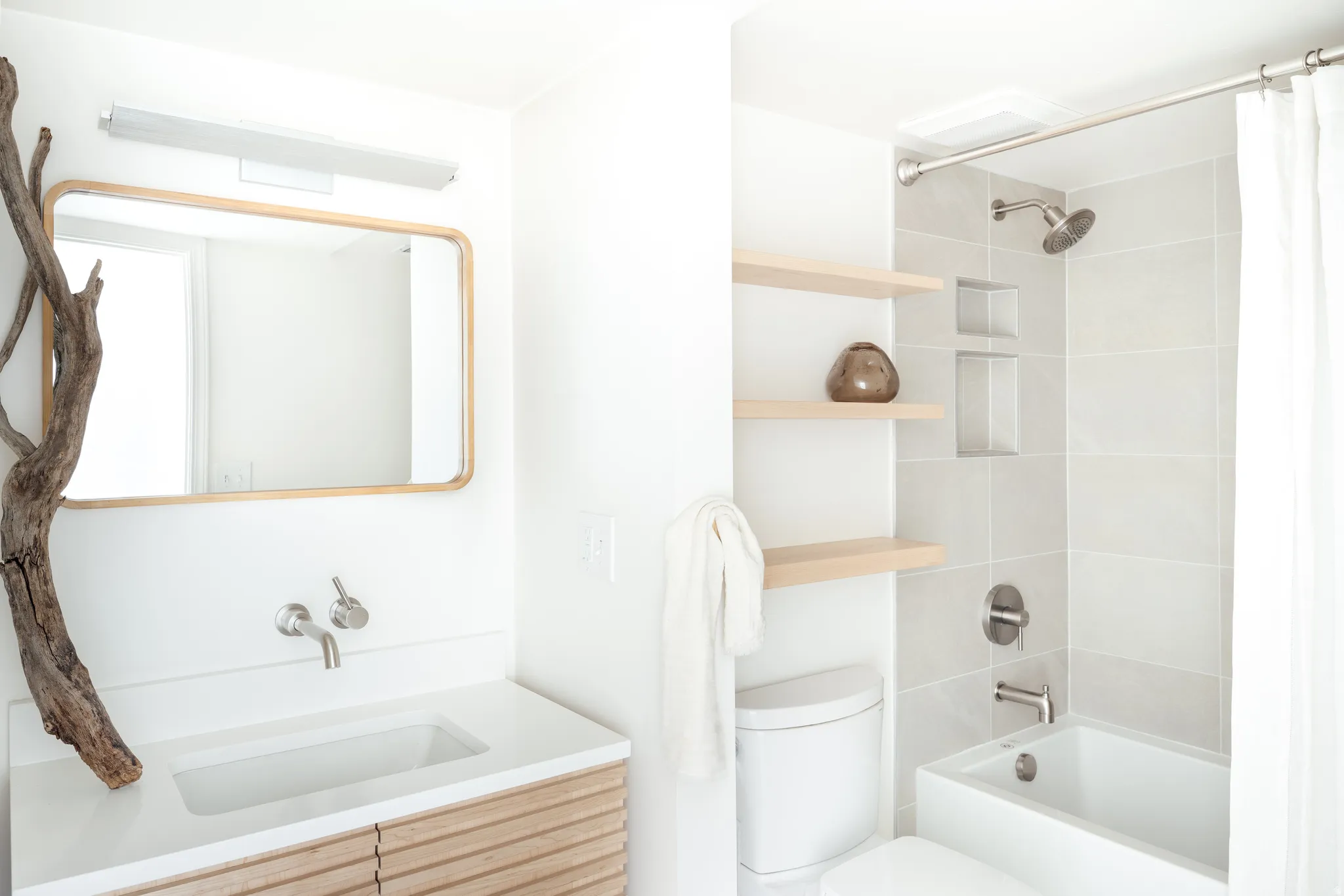 Bathroom featuring a wall-mounted faucet, integrated sink, and wood-finish vanity with horizontal slat detailing