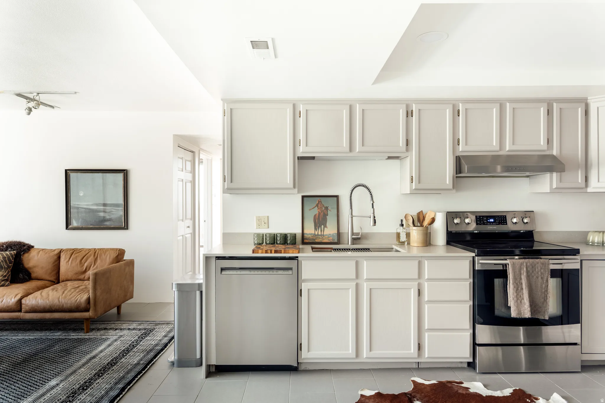 Kitchen featuring light-toned cabinetry and countertops, stainless steel appliances, and a modern gooseneck faucet