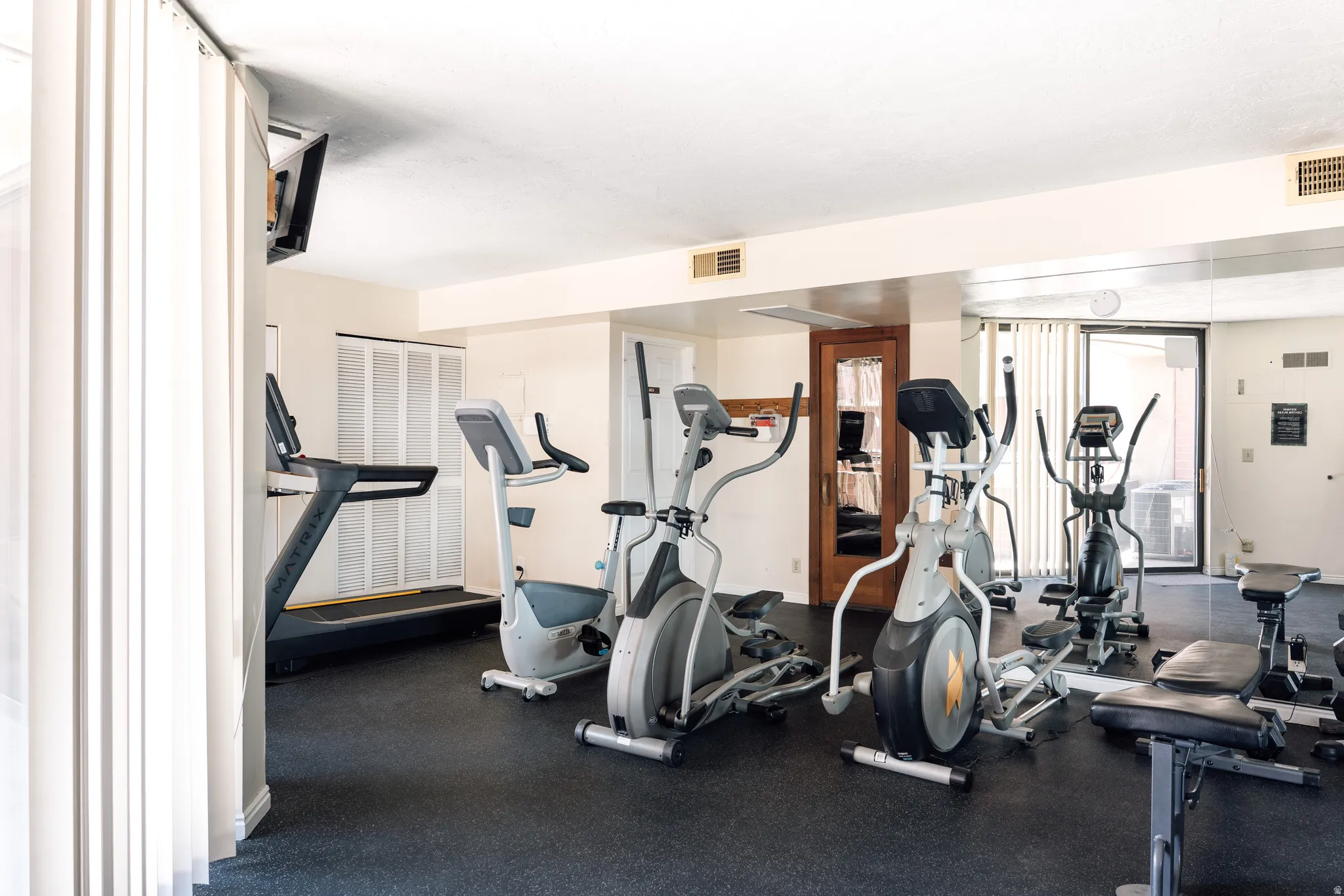 Dedicated fitness center featuring rubber flooring, a mirrored wall, and recessed lighting