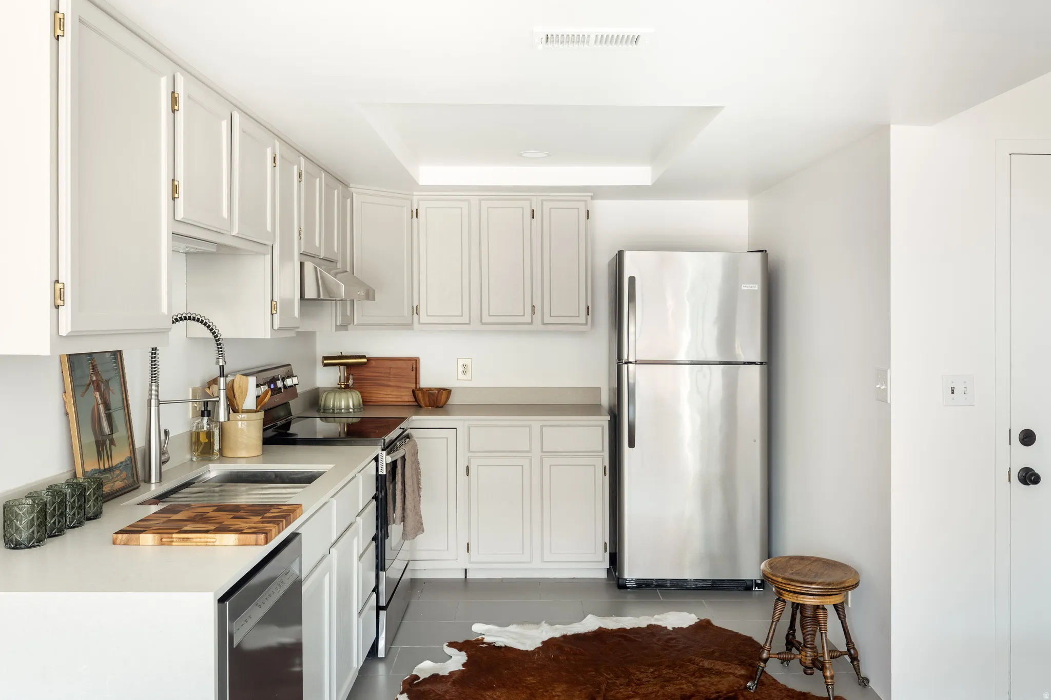 Light-toned cabinetry with brass-tone hardware, stainless steel appliances, and light-colored countertops