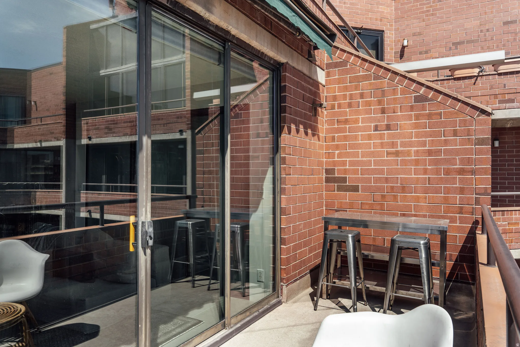 Private outdoor patio featuring a sliding glass door, brick walls, and a protective awning