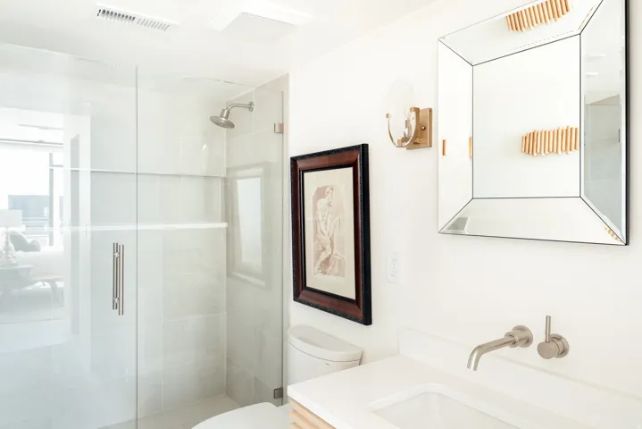 Contemporary bathroom featuring a glass-enclosed shower with tile surround, a wall-mounted faucet, and a vessel sink set into a white countertop