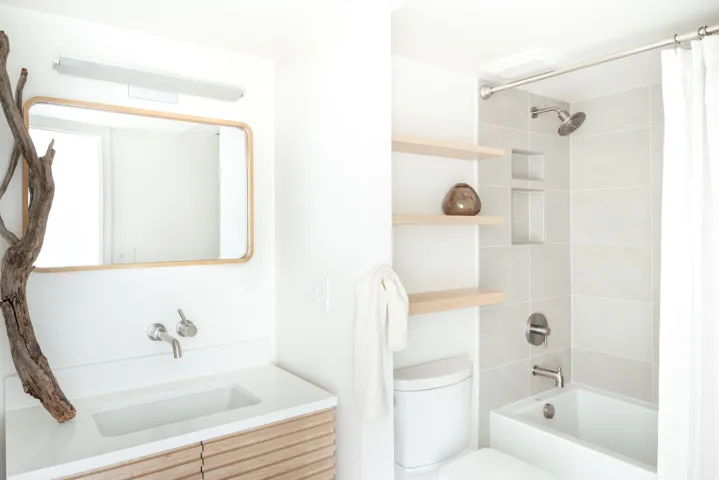 Bathroom featuring a wall-mounted faucet, integrated sink, and wood-finish vanity with horizontal slat detailing