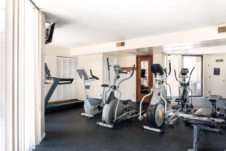 Dedicated fitness center featuring rubber flooring, a mirrored wall, and recessed lighting