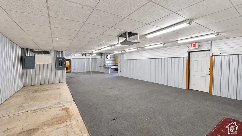 Spacious interior featuring a dropped ceiling, fluorescent lighting, and a combination of corrugated metal and slat walls
