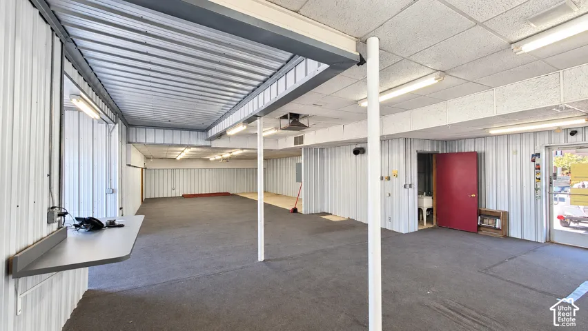 Large open space featuring a dropped ceiling, fluorescent lighting, and corrugated metal wall finishes