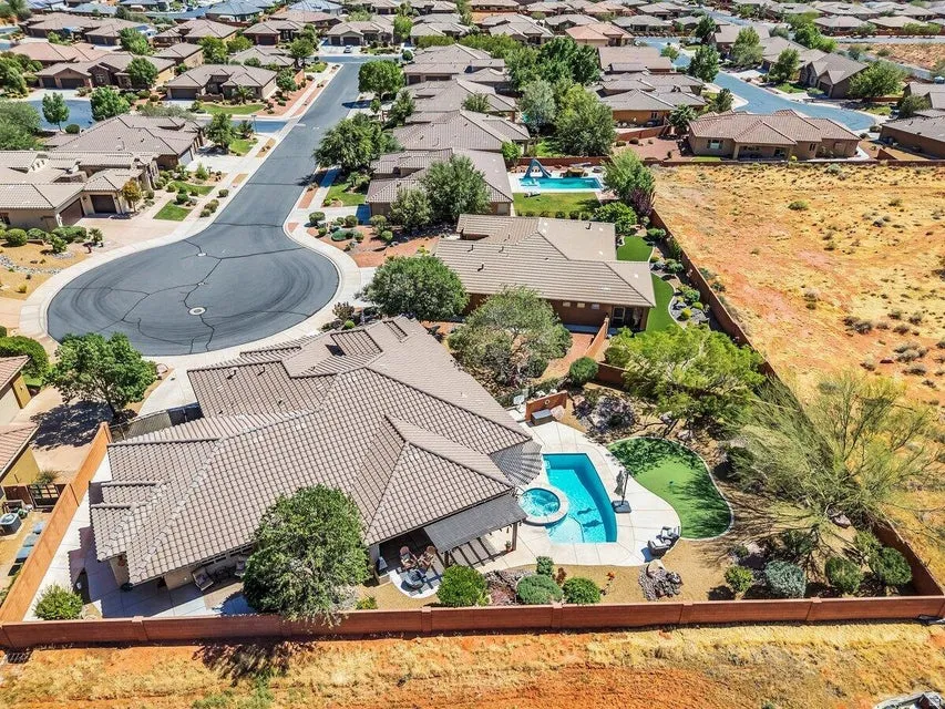 Terracotta-tiled roof property featuring a private swimming pool with integrated spa, adjacent artificial turf area, and surrounding mature landscaping