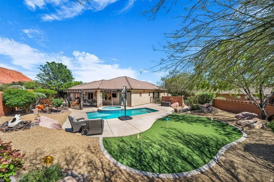 Exterior featuring a private pool with an integrated spa, an artificial turf putting green, a covered patio, and desert-style landscaping