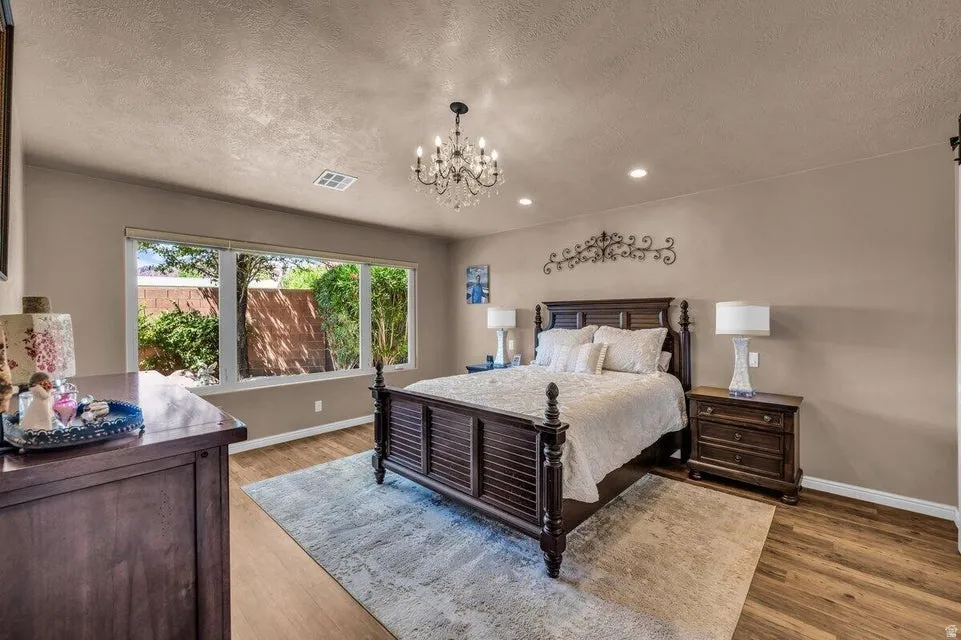 Bedroom featuring large windows, wood-finish flooring, recessed lighting, and a crystal-adorned chandelier