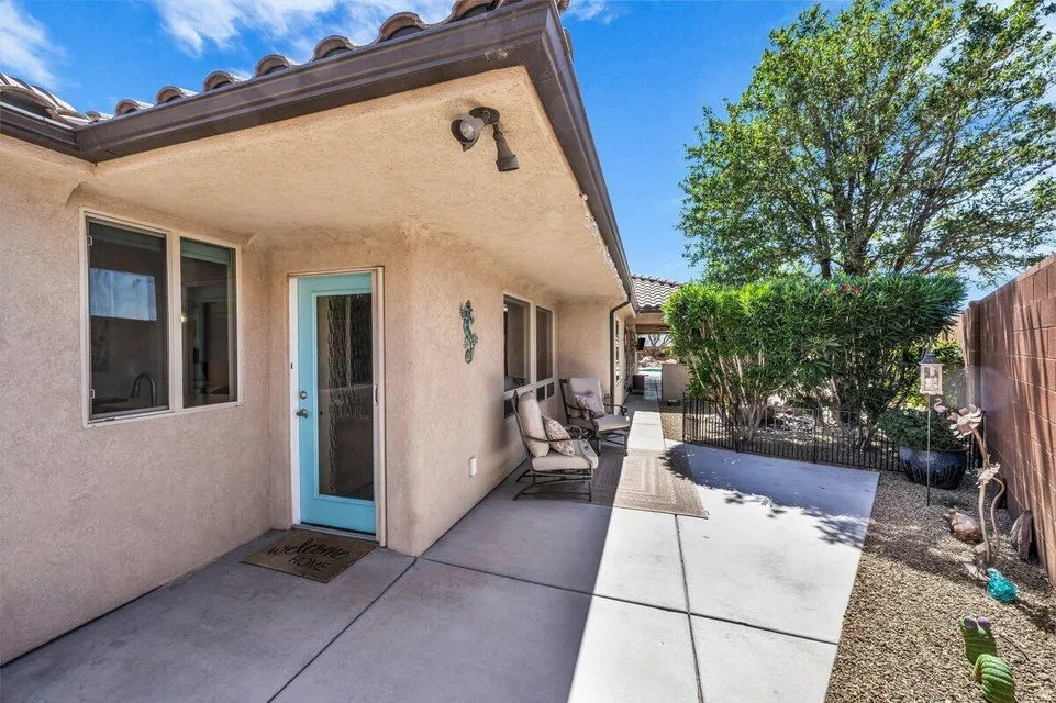 Covered patio area with concrete flooring, stucco exterior, and a vibrant turquoise door