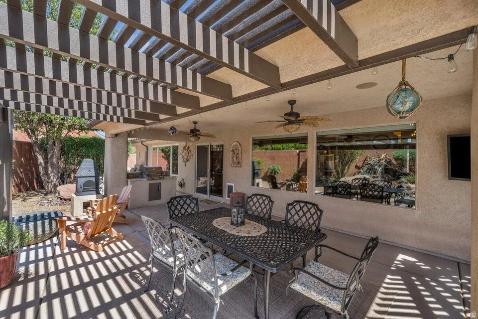 Covered patio featuring a built-in outdoor kitchen with grill, dual ceiling fans, recessed lighting, and a slatted pergola extension