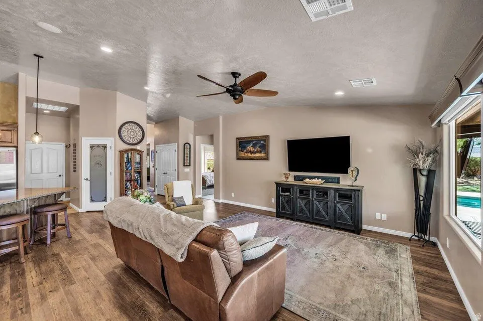 Spacious living area featuring wood-finish flooring, recessed lighting, and a ceiling fan