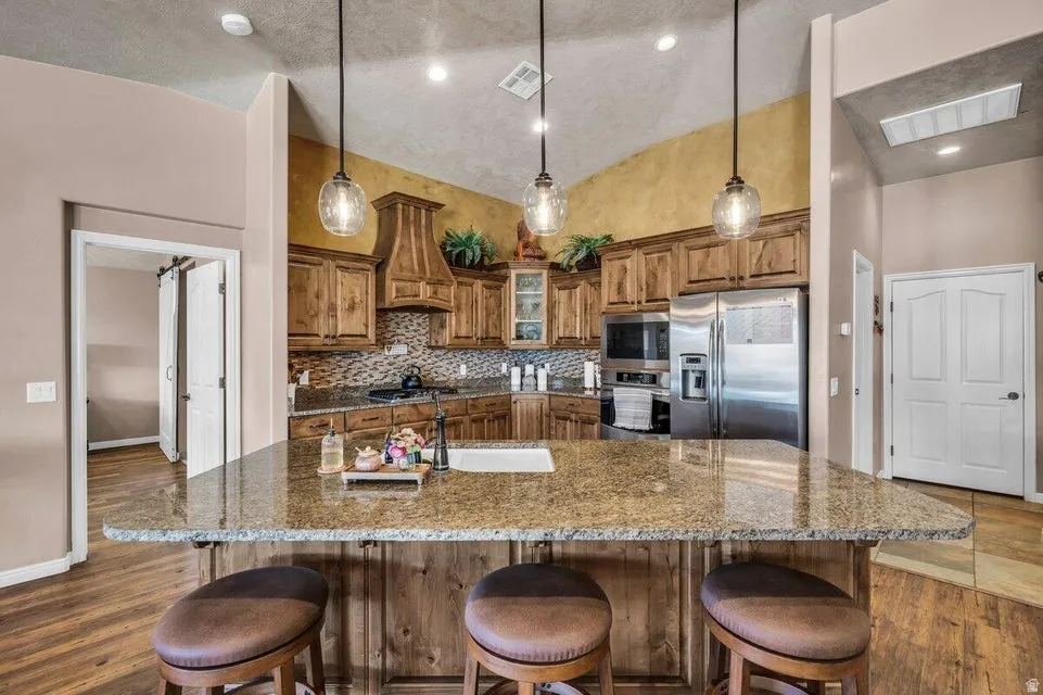 Kitchen featuring a central island with an undermount sink, granite countertops, and three pendant lights