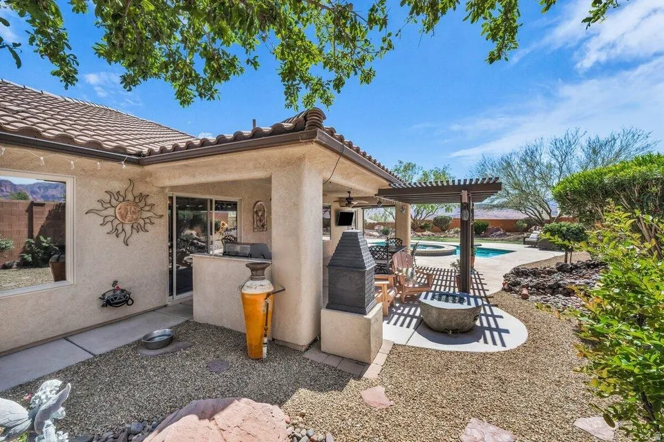 Outdoor living area featuring a covered patio, built-in outdoor kitchen, pergola-covered seating, and a resort-style pool with integrated spa
