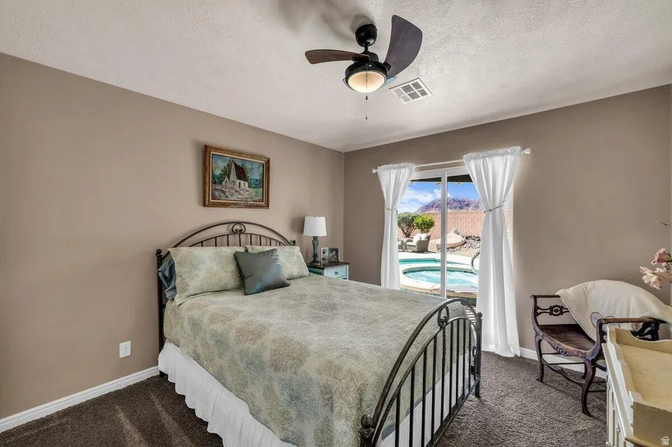 Carpeted bedroom featuring a sliding glass door with backyard access, a ceiling fan with integrated lighting, and neutral wall tones