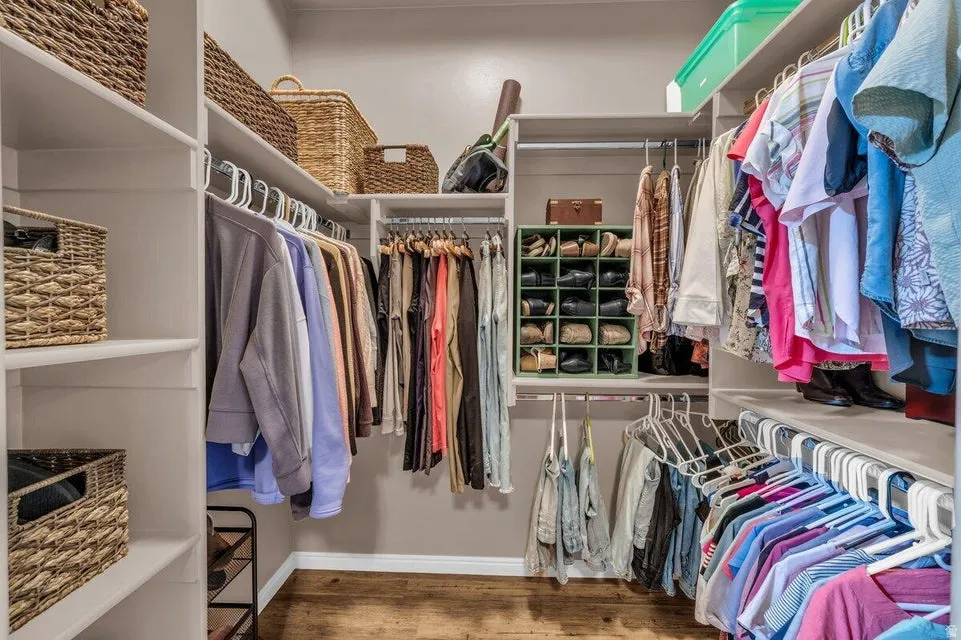 Custom closet system featuring multiple hanging rods, integrated shelving, and wood-finish flooring