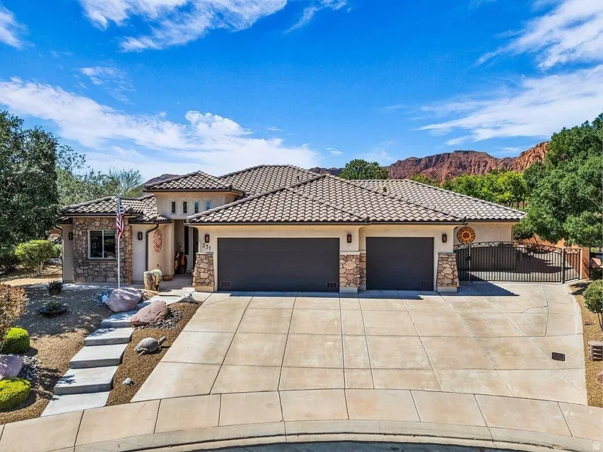 Mediterranean-style residence featuring a tile roof, stucco and stone facade, and integrated two-car garage