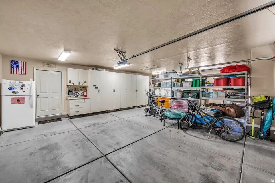 Spacious garage featuring extensive built-in cabinetry, concrete flooring, and overhead lighting