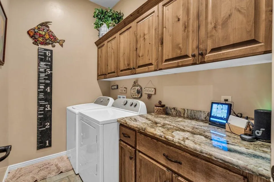 Laundry room featuring a built-in granite countertop, under-cabinet lighting, and wood cabinetry with dark hardware