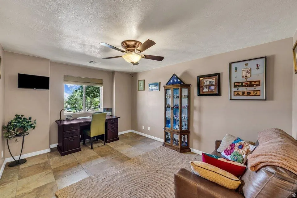 Room featuring large window, neutral-toned walls, ceiling fan, and tile flooring