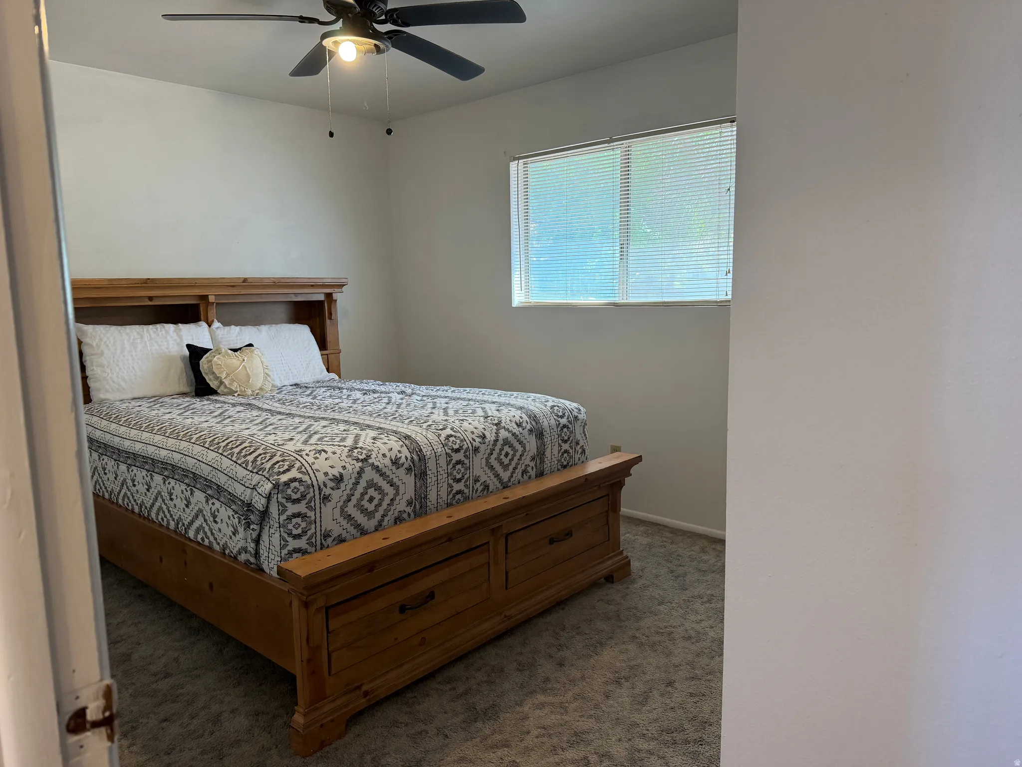 Bedroom featuring neutral-toned carpeting, light-colored walls, and a window with blinds