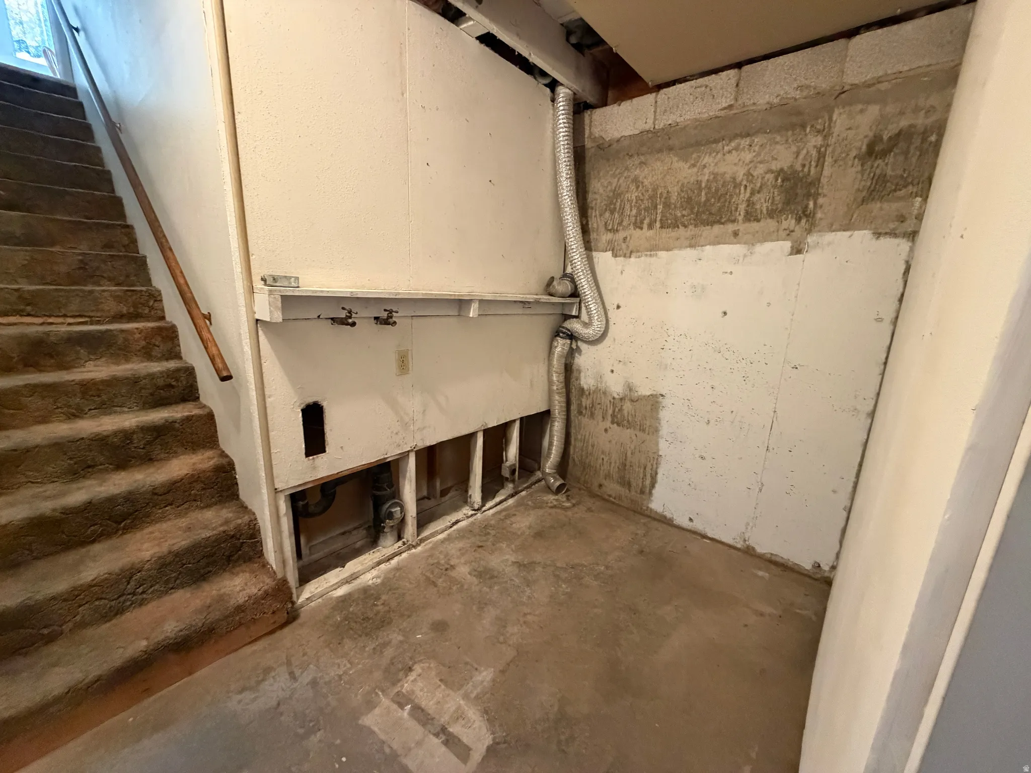 Utility area featuring exposed plumbing and concrete flooring