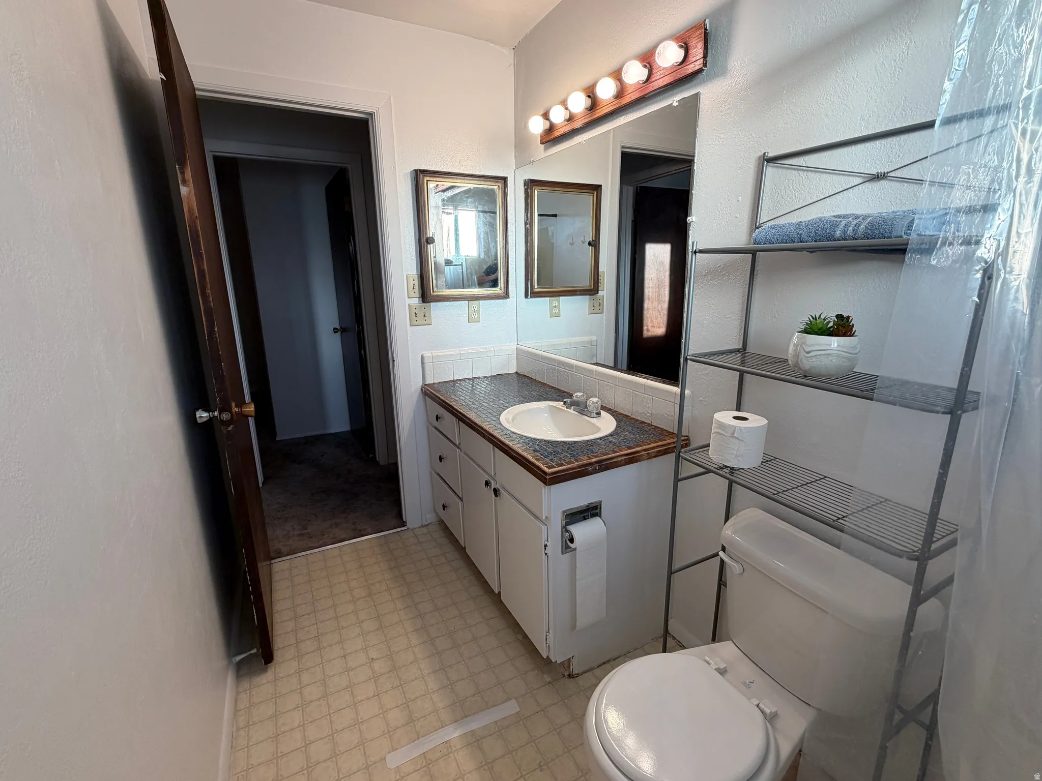 Bathroom vanity with an integrated sink, textured countertop, and full-width mirror