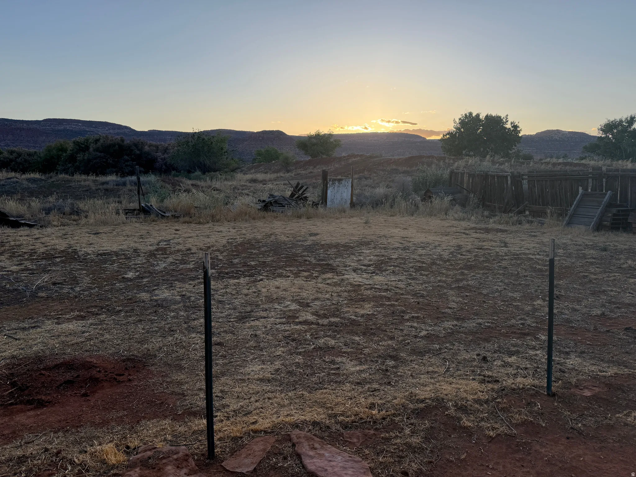 Expansive outdoor space featuring natural landscaping, distant mountainous terrain, and visible fencing elements