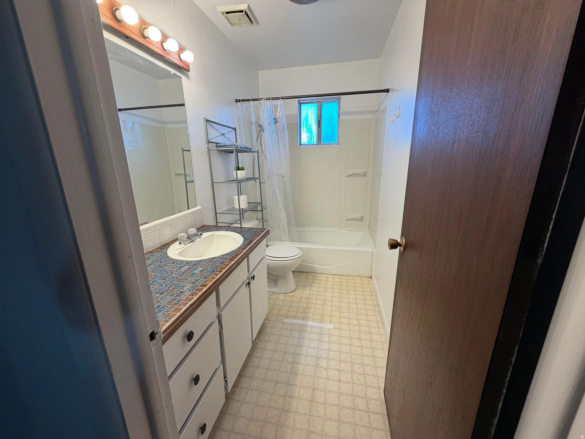 Bathroom featuring a single vanity with an integrated sink, patterned countertop, and white cabinetry