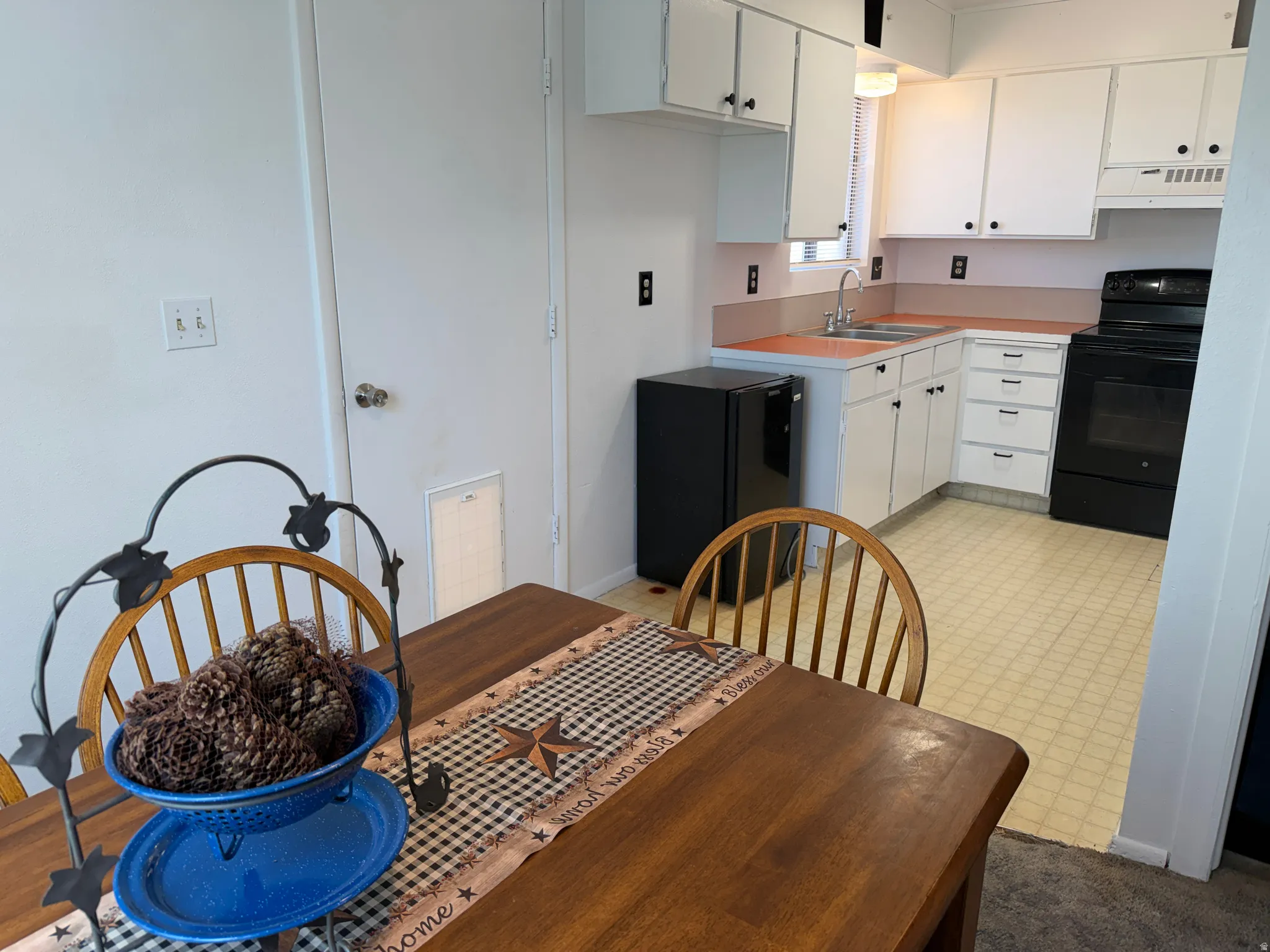 Kitchen space featuring white cabinetry, a double basin sink, and a black electric range