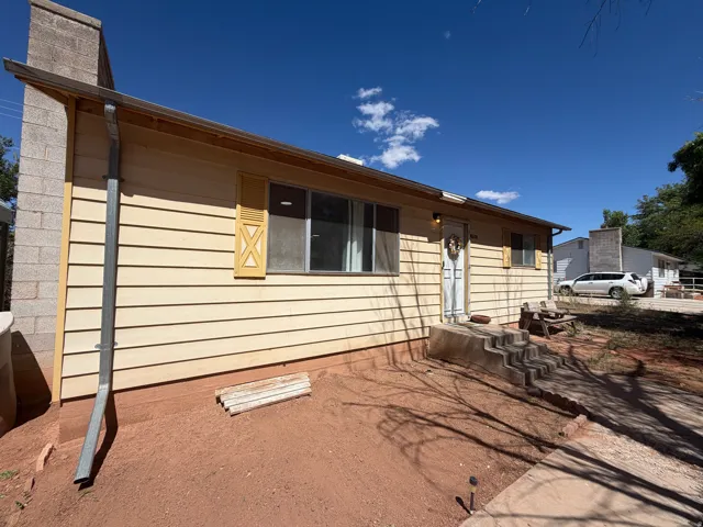 Front exterior featuring horizontal siding, decorative shutters, a concrete entry with steps, and a visible chimney structure