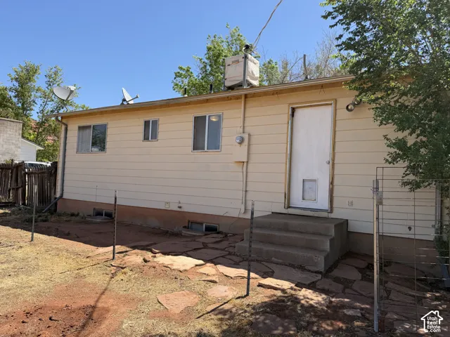 Rear exterior featuring beige horizontal siding, a white entry door with a pet door, and three windows