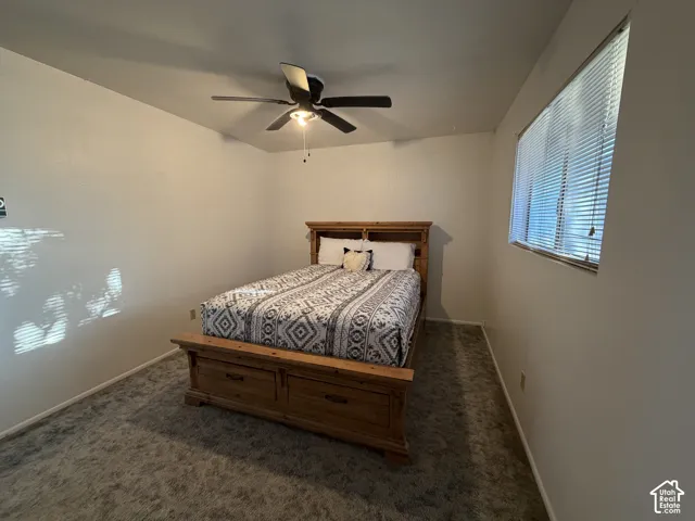 Room featuring neutral wall tones, textured carpeting, a window with blinds, and a ceiling fan with integrated lighting