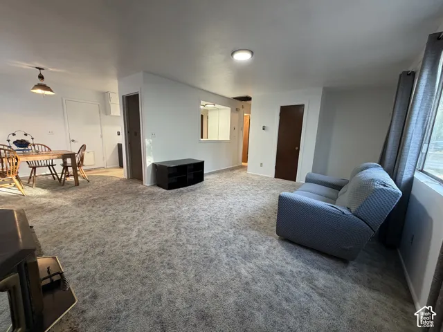 Open-concept living space featuring light gray carpeting, a built-in pass-through window, and a central ceiling light fixture