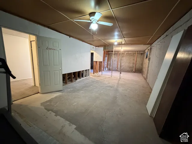 Unfinished basement space featuring exposed concrete flooring, suspended ceiling panels, and visible framing