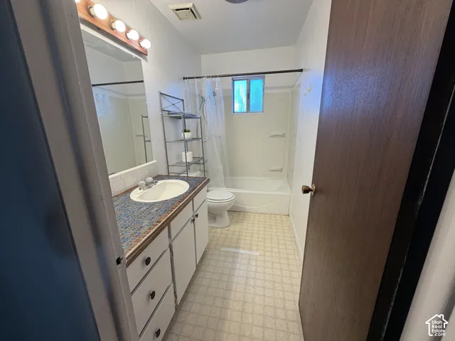 Bathroom featuring a single vanity with an integrated sink, patterned countertop, and white cabinetry
