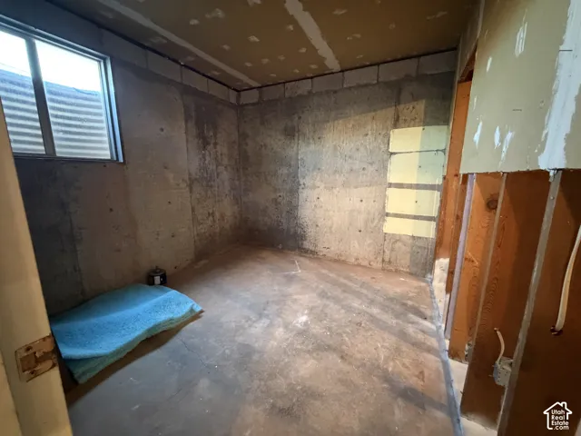 Concrete foundation walls featuring a small window with a window well