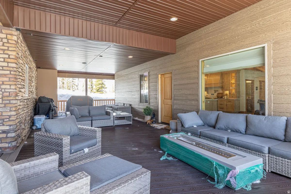 Spacious covered patio featuring a stone veneer exterior, wood-finish decking, and a wood-paneled ceiling with recessed lighting
