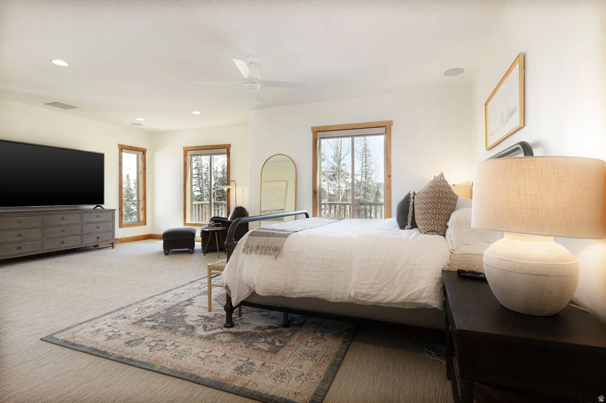 Carpeted sleeping area featuring multiple windows with wood trim, a built-in ceiling fan, recessed lighting, and an integrated entertainment area