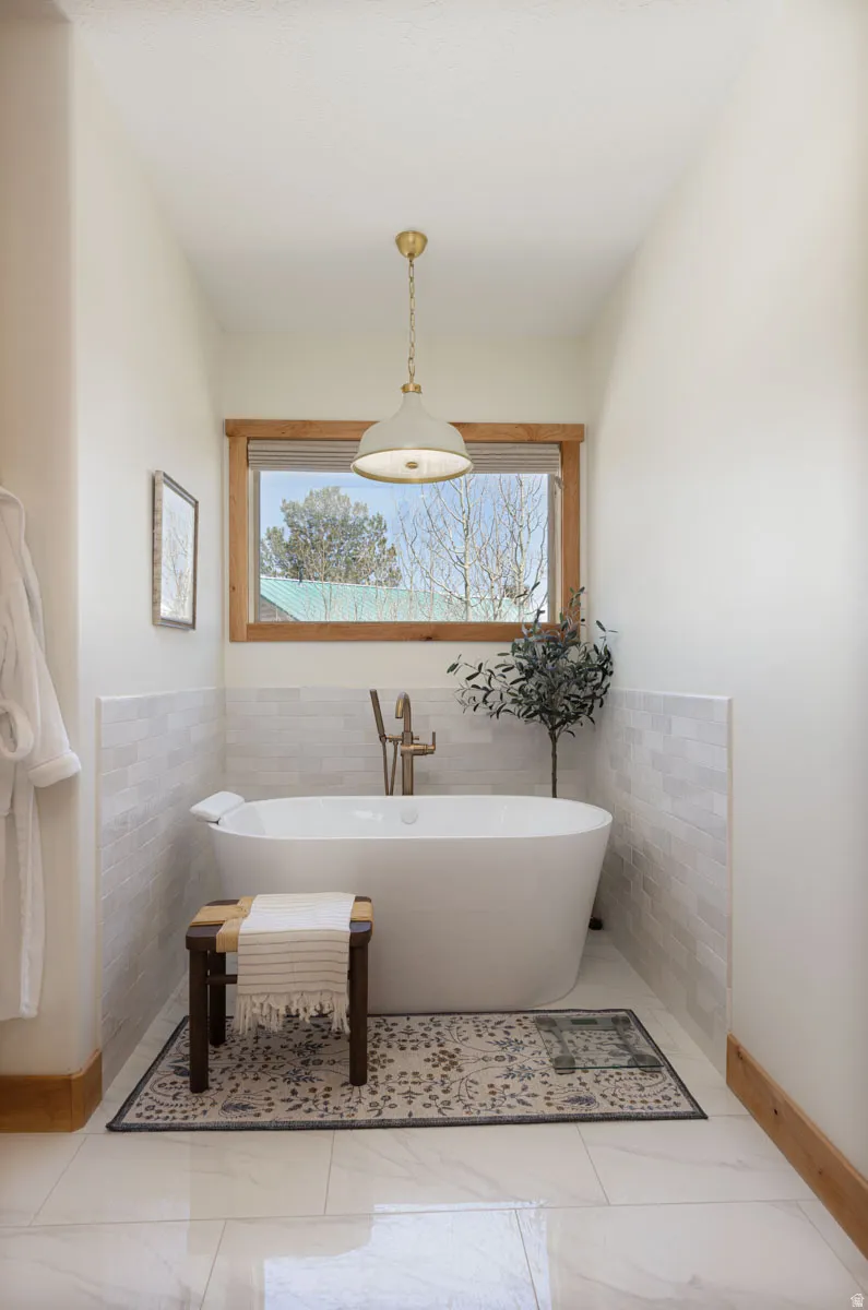 Freestanding white soaking tub with a wall-mounted brass faucet
