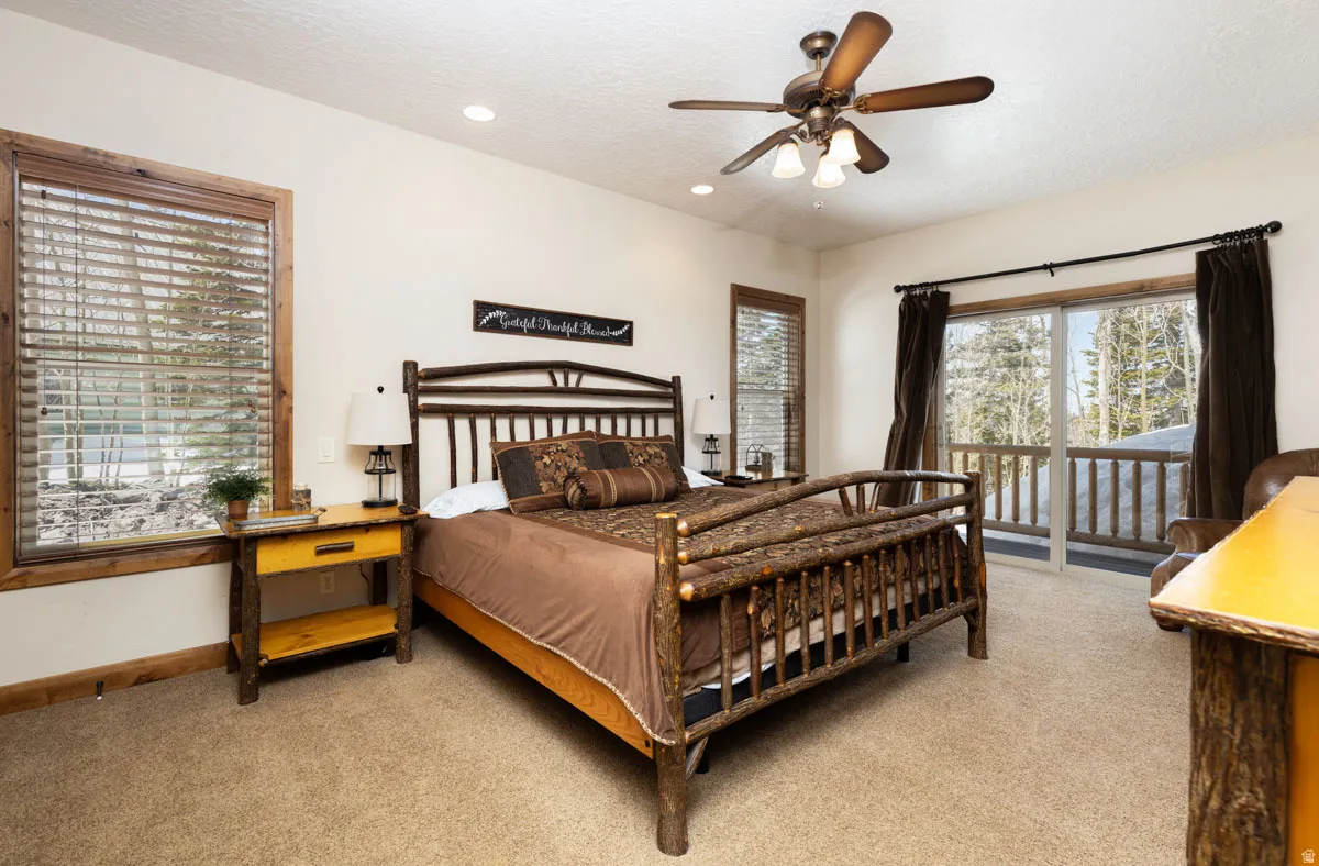 Spacious bedroom featuring light beige walls and textured carpeting