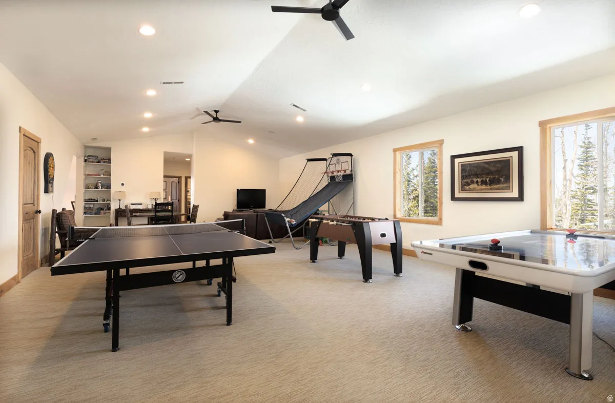 Spacious recreation room featuring recessed lighting, a vaulted ceiling, and two ceiling fans