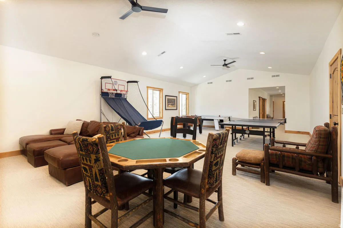 Spacious room featuring vaulted ceilings, recessed lighting, two ceiling fans, and light-toned carpeting