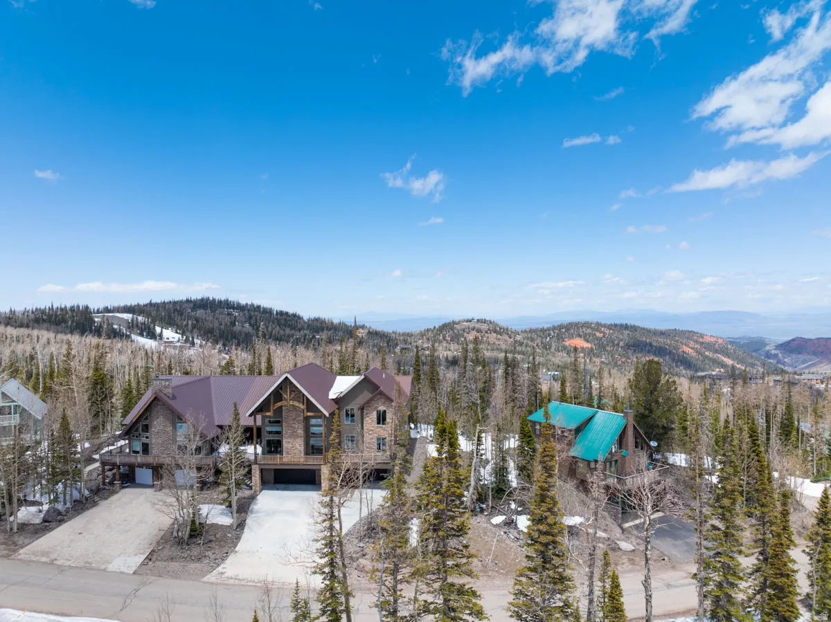Expansive mountain property featuring a stone and wood-clad exterior with a dark brown roof